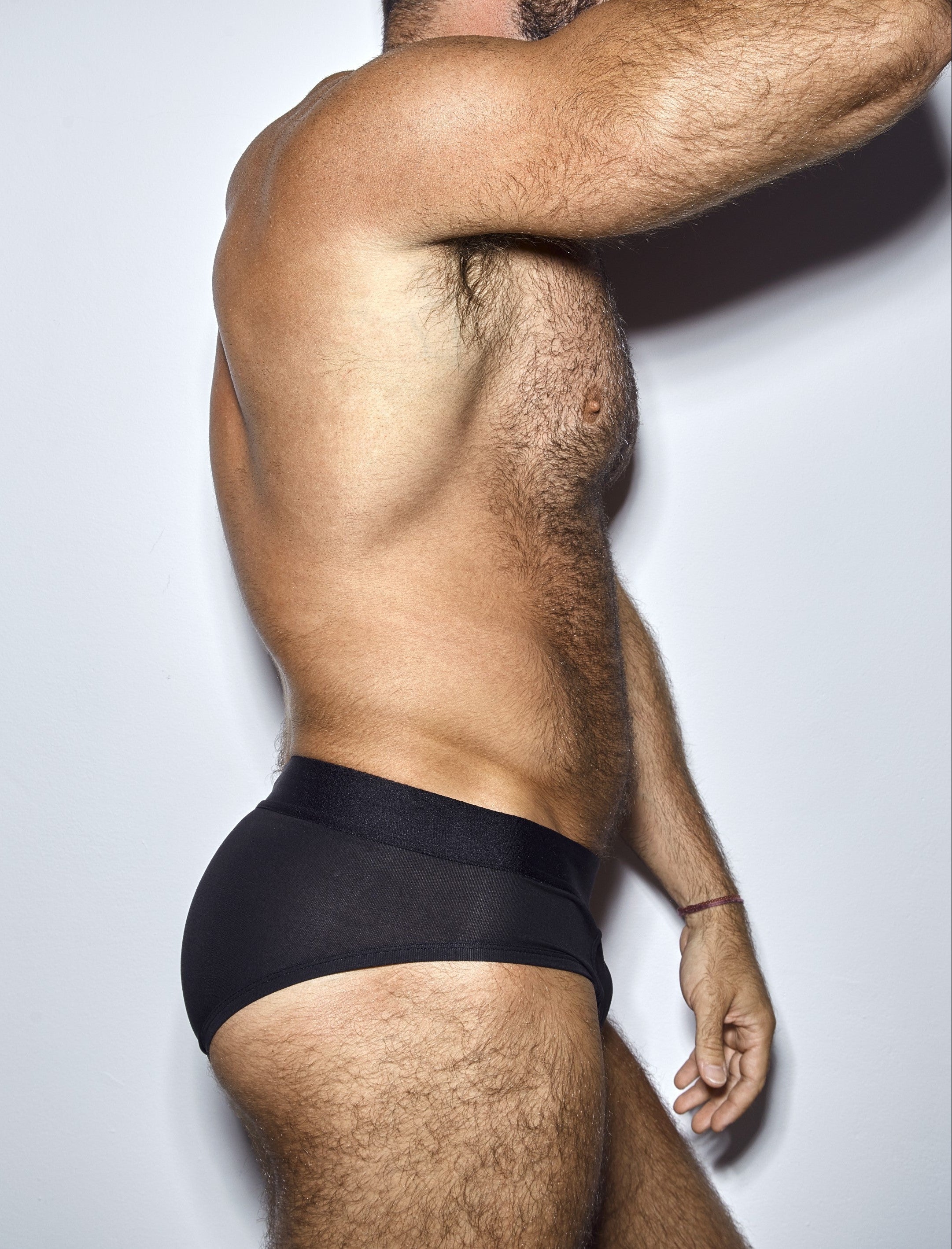 Man wearing a black underwear on a plain background