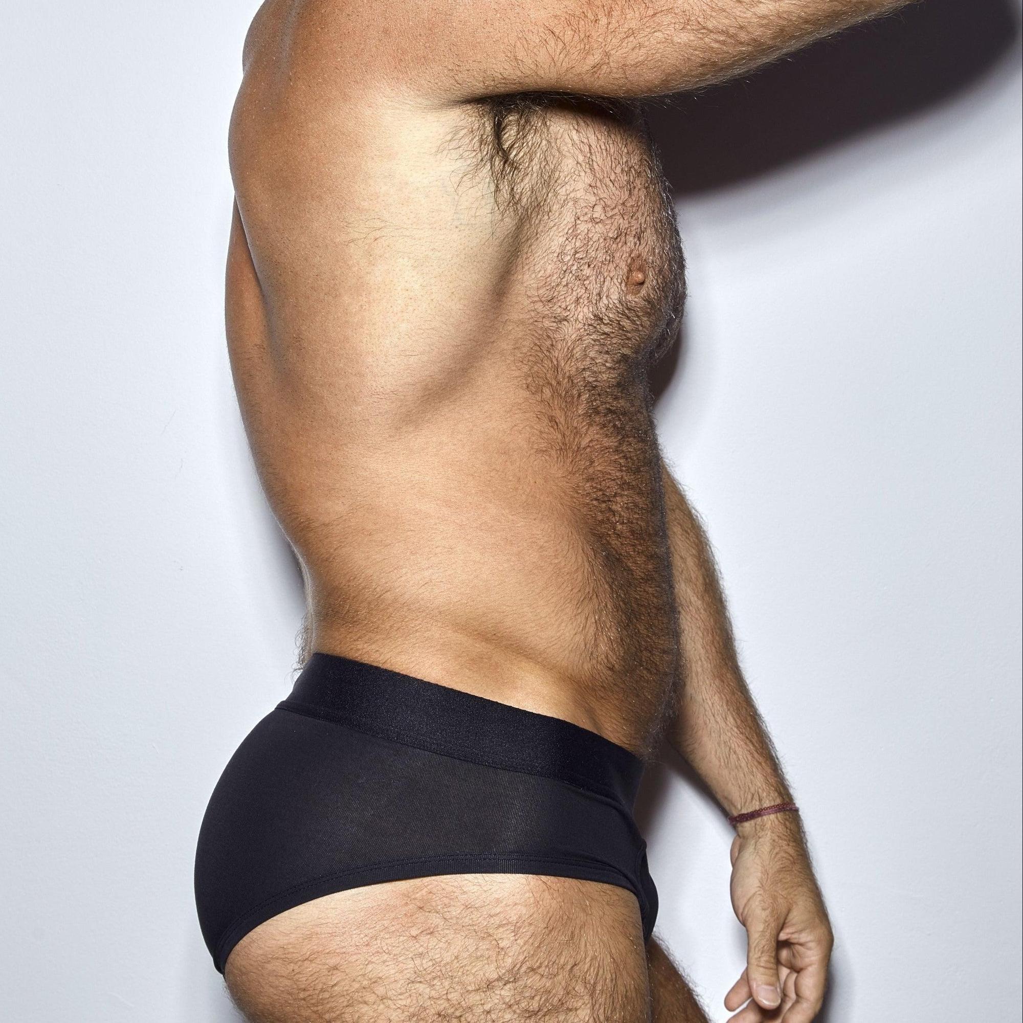 Man wearing a black underwear on a plain background
